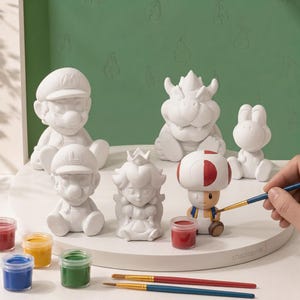 May include: A set of six unpainted ceramic figurines featuring Mario, Luigi, Princess Peach, Bowser, Yoshi, and Toad. One Toad figurine is partially painted with red and blue colours. Includes small paint pots and two brushes for crafting.