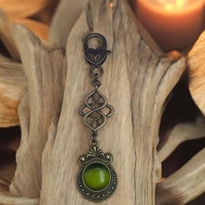 May include: A bronze key chain with a green glass cabochon and an intricate Celtic knot design.