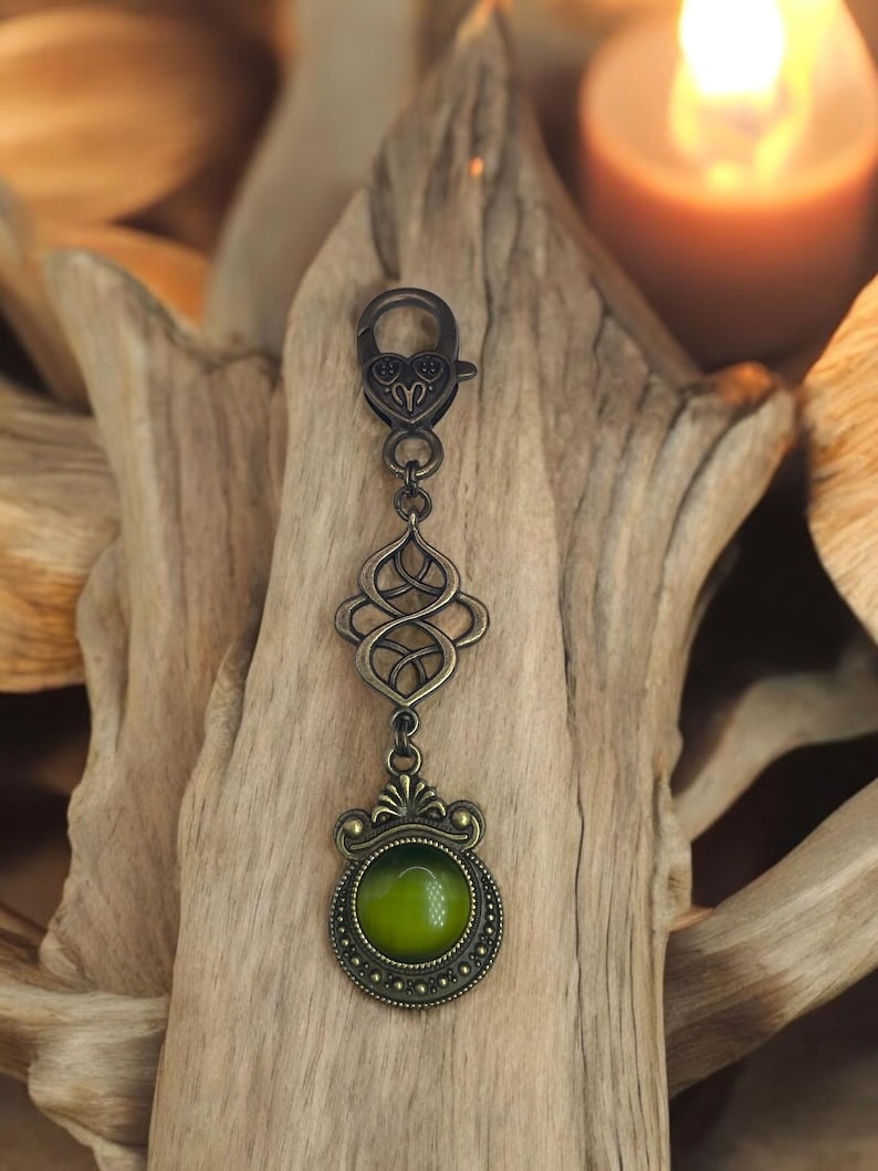 May include: A bronze key chain with a green glass cabochon and an intricate Celtic knot design.