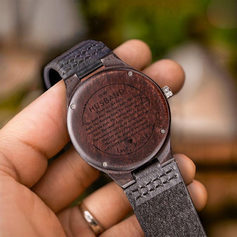 Pode incluir: Um rel&oacute;gio de pulso de madeira com mostrador castanho escuro e bracelete de couro preto. O mostrador do rel&oacute;gio &eacute; gravado com as palavras "TO MY HUSBAND" e uma mensagem de amor. O rel&oacute;gio &eacute; um presente atencioso.