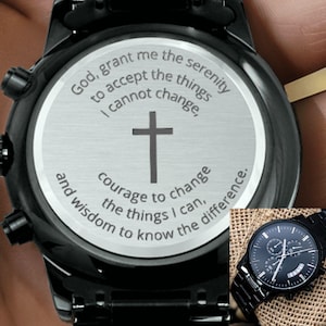 Puede incluir: Reloj de pulsera negro con parte trasera de acero inoxidable. La esfera del reloj tiene una cruz y el texto "Dios, concédeme la serenidad para aceptar las cosas que no puedo cambiar, el valor para cambiar las cosas que puedo y la sabiduría para conocer la diferencia."
