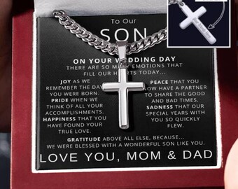 May include: A silver cross necklace in a black box with a message to a son on his wedding day. The message reads "On your wedding day there are so many emotions that fill our hearts today... Joy as we remember the day you were born. Pride when we think of all your accomplishments. Happiness that you have found your true love. Peace that you now have a partner to share the good and bad times. Sadness that our special years with you so quickly flew. Gratitude above all else, because... we were blessed with a wonderful son like you. Love you, Mom & Dad".