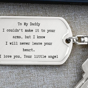 May include: A silver-colored dog tag-shaped keychain with the text "To My Daddy" and a heartfelt message. The text is in a simple, easy-to-read font. The keychain is attached to a metal ring and a key.