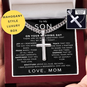 May include: A silver cross pendant necklace displayed in a mahogany-style luxury box. The box contains a heartfelt message from "Mom" to "Son" on his wedding day. The necklace is shown with a personalized engraving option.