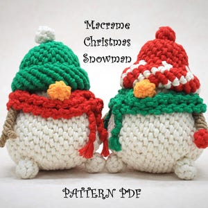 Puede incluir: Dos muñecos de nieve de macramé hechos a mano. Cada muñeco de nieve tiene un cuerpo blanco, una bufanda roja y un gorro verde. Un gorro tiene un pompón blanco. El texto "Macrame Christmas Snowman" y "PATTERN PDF" son visibles.
