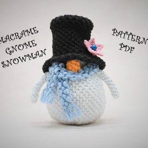 Könnte beinhalten: Ein handgefertigter Makramee-Schneemann mit schwarzem Zylinder, blauem Schal und oranger Nase. Der Schneemann hat weiße Arme und einen weißen Körper. Der Text "MACRAME GNOME SNOWMAN" und "PATTERN PDF" sind zu sehen.