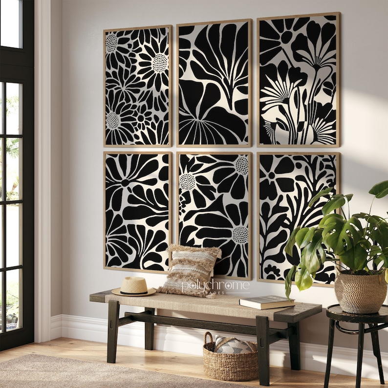 May include: A set of six black and white floral print wall art pieces in wooden frames. The prints are arranged in a grid pattern on a white wall above a wooden bench.