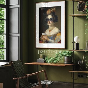 Op de afbeelding: Een ingelijste print van een vrouw met een zonnebril en een parelketting, die een kopje koffie vasthoudt. De vrouw draagt een blauwe en gele jurk met een bloemenhoed. De print is op een groene muur met een houten plank en een plant in een pot.