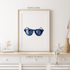 May include: A watercolor painting of a pair of blue sunglasses on a white background. The painting is framed and hanging on a white wall.