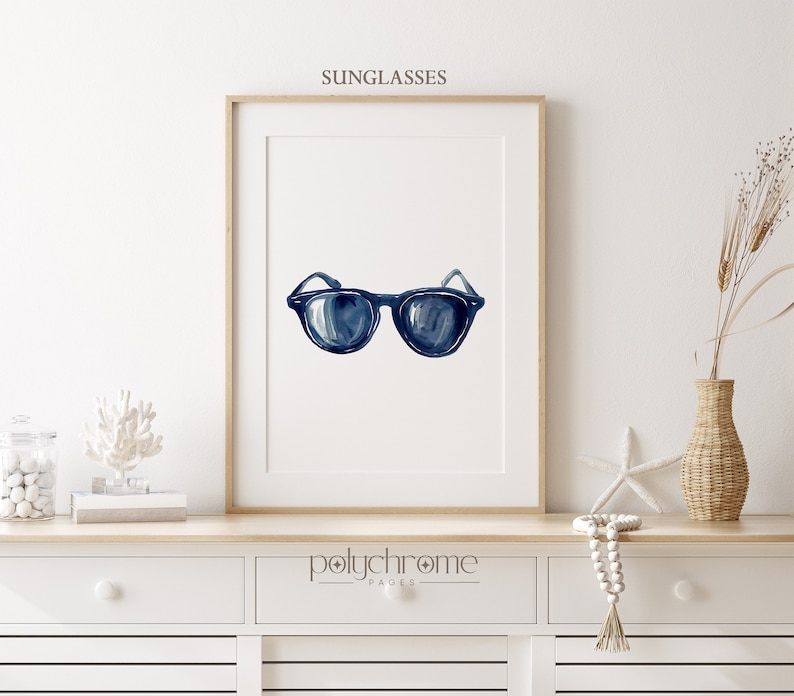 May include: A watercolor painting of a pair of blue sunglasses on a white background. The painting is framed and hanging on a white wall.