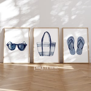 May include: Three framed prints with a nautical theme. The first print features a pair of blue sunglasses. The second print features a blue and white striped tote bag. The third print features a pair of blue flip flops.