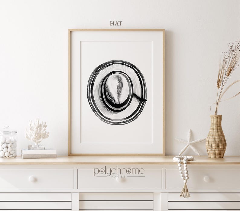 Puede incluir: Impresi&oacute;n de arte abstracto en blanco y negro de un c&iacute;rculo con anillos conc&eacute;ntricos. La impresi&oacute;n est&aacute; enmarcada y colgada en una pared blanca. El texto "HAT" est&aacute; escrito encima de la impresi&oacute;n.