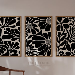 May include: Three framed black and white abstract floral prints with a cream background. The prints are arranged in a row on a white wall.