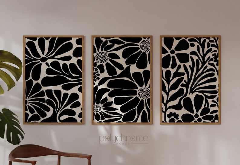 May include: Three framed black and white abstract floral prints with a cream background. The prints are arranged in a row on a white wall.