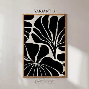 May include: Black and white abstract art print with a floral design. The print is framed in a natural wood frame. The print is titled "VARIANT 2" and is by the brand "polychrome_paper".