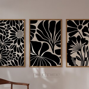 May include: Three framed prints with black and white floral designs. The prints are set against a white wall.