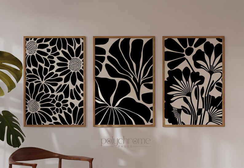 May include: Three framed prints with black and white floral designs. The prints are set against a white wall.