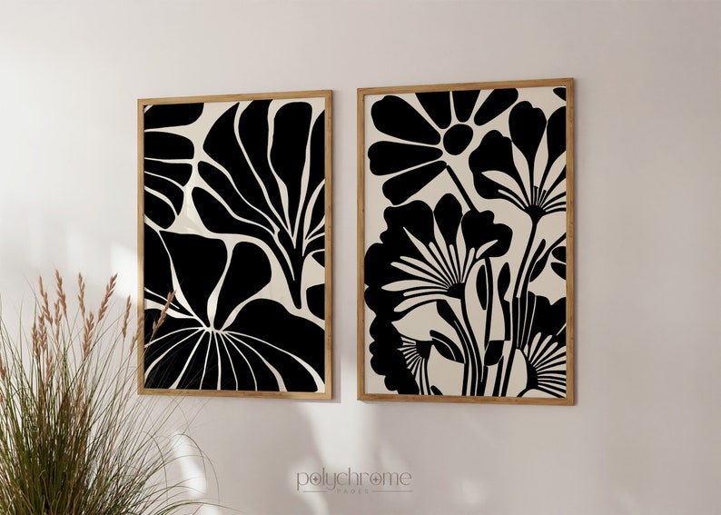May include: Two black and white abstract floral prints in wooden frames. The prints feature stylized flowers and leaves.