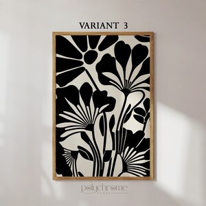 May include: Black and white abstract floral print art in a wooden frame. The print features stylized flowers with large petals and stems.