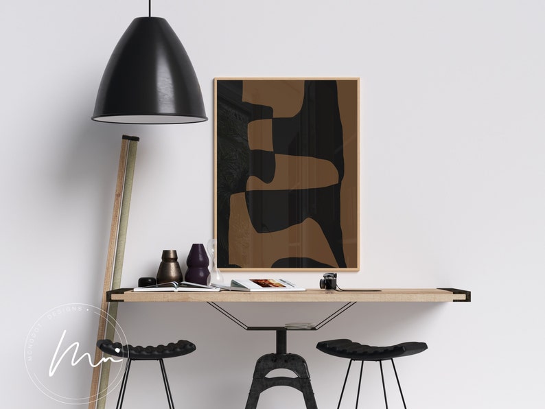 May include: A minimalist home office with a wooden desk, two black metal bar stools, and a framed abstract print with brown and black geometric shapes.