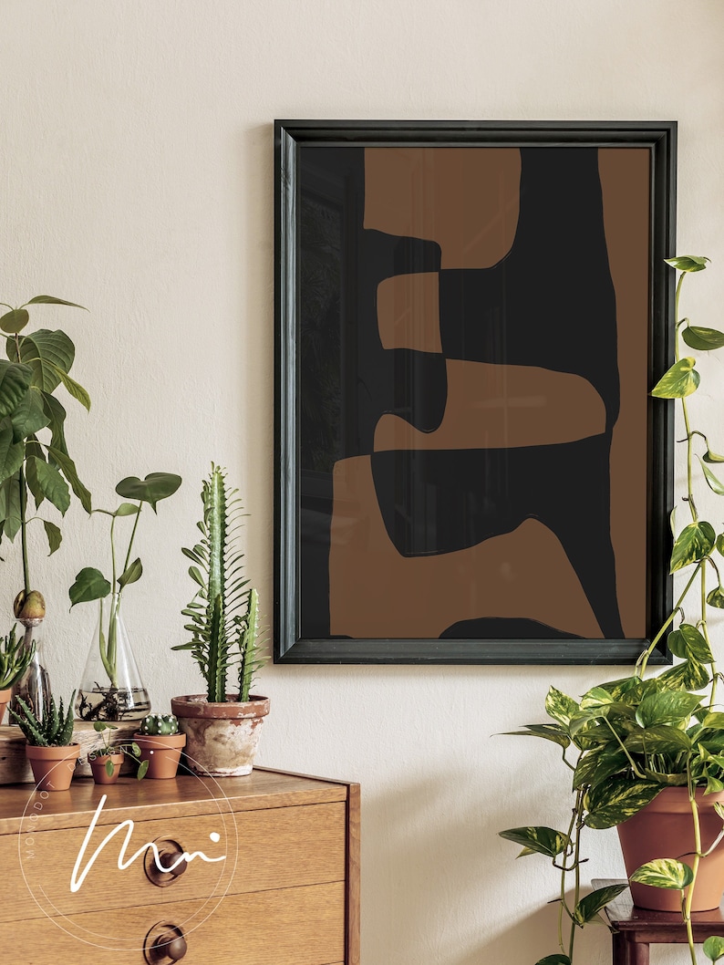May include: A framed abstract art print with brown and black geometric shapes. The print is hanging on a white wall above a wooden dresser with plants.