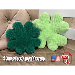 Könnte beinhalten: Zwei blütenförmige Kissen in Grüntönen. Eines ist tiefgrün, das andere hellgrün. Die Kissen befinden sich auf einer gemusterten Oberfläche. Der Text auf dem Bild lautet "Crochet pattern".