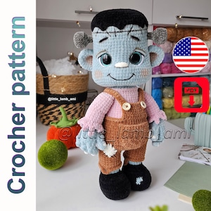 Pode incluir: Boneca Frankenstein de crochê feita à mão em azul claro, preto e castanho. A boneca usa uma camisa rosa e macacão castanho. A imagem inclui o texto "Crochet pattern" e um ícone de download PDF.