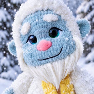 Close-up of a crochet yeti's light blue face framed by fluffy white fur and a long silky beard. Large glossy eyes, a rounded pink nose, and an embroidered smile stand out against a snowy forest background, with a yellow scarf below.