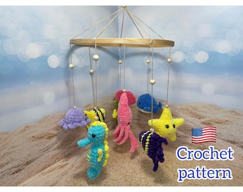 May include: A wooden mobile with crocheted sea creatures hanging from it. The creatures include a purple octopus, a yellow starfish, a blue seahorse, a pink squid, a blue whale, and a purple fish. The mobile is hanging from a wooden ring and is suspended from the ceiling.