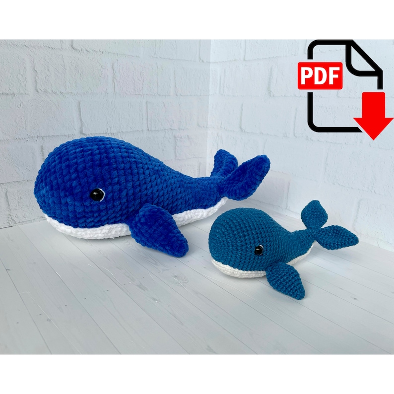 May include: A crochet pattern for making two blue whale plushies. The larger whale is lying down with its tail curled up. The smaller whale is sitting up with its tail curled to the side. Both whales have white bellies and black eyes.