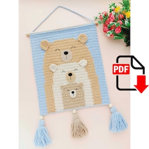 May include: Crochet wall hanging featuring three bears in a stack. The bears are brown, white, and brown, with smiling faces. The hanging has blue tassels.