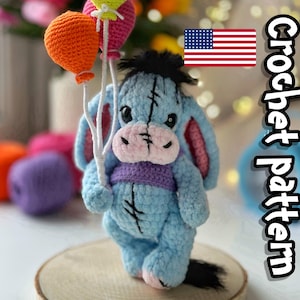 Könnte beinhalten: Gehäkeltes Eeyore-Plüschtier in Hellblau, das orangefarbene und rosa Ballons hält. Das Plüschtier hat eine lila Weste, rosa Innenohren und schwarze Nahtdetails. Der Text "Crochet pattern" ist sichtbar.