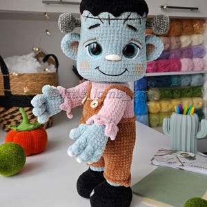 Soft crochet Frankenstein toy made with velvet yarn, wearing brown overalls and a pink shirt. Crochet pattern for beginners and intermediates, detailed and easy to follow.