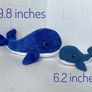 May include: Two crocheted whale plushies, one blue and white, measuring 9.8 inches, and one smaller blue and white whale measuring 6.2 inches.