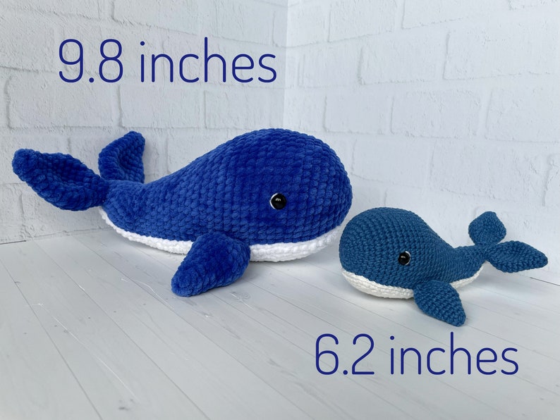May include: Two crocheted whale plushies, one blue and white, measuring 9.8 inches, and one smaller blue and white whale measuring 6.2 inches.