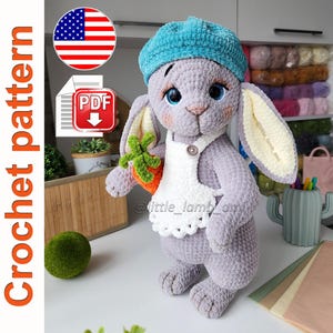 Peut inclure: Un lapin crocheté gris, portant un béret bleu et un tablier blanc, tenant une carotte. Le lapin a de grands yeux bleus et des joues roses. L'image comprend le texte "Crochet pattern" et une icône de téléchargement PDF.