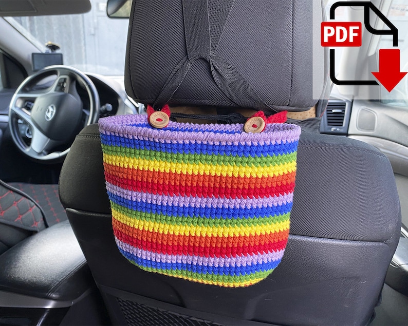 May include: A rainbow striped crocheted car seat organizer with two wooden buttons hanging from the headrest of a car seat.