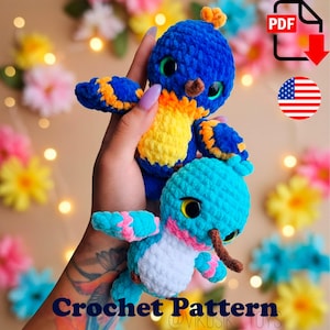 May include: Two plush crochet bird toys featuring soft yarn textures. The top bird is blue with a yellow chest and orange wing accents. The bottom bird is turquoise with a white chest and pink wing accents. Both have large dark eyes and brown beaks.