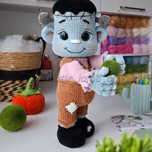 Crocheted Frankenstein plush holding a green ball, surrounded by cozy yarn and autumn decor. Fun Halloween crochet project with clear step-by-step instructions.