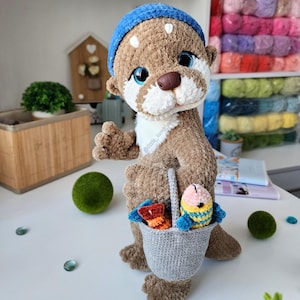 Handmade crochet otter with a grey yarn bucket full of colorful crocheted fish. Soft and cuddly amigurumi project for kids or collectors.