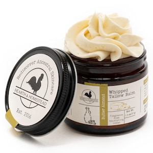 Könnte beinhalten: Ein dunkel bernsteinfarbenes Glas mit geschlagener Talgcreme und schwarzem Deckel. Das Etikett zeigt Hearth & Homestead, Rediscover Ancestral Skincare, Est. 2016, Butter Almond und Net Wt. 1.3 oz/37 g. Die weiße Creme ist oben im Glas aufgetürmt.