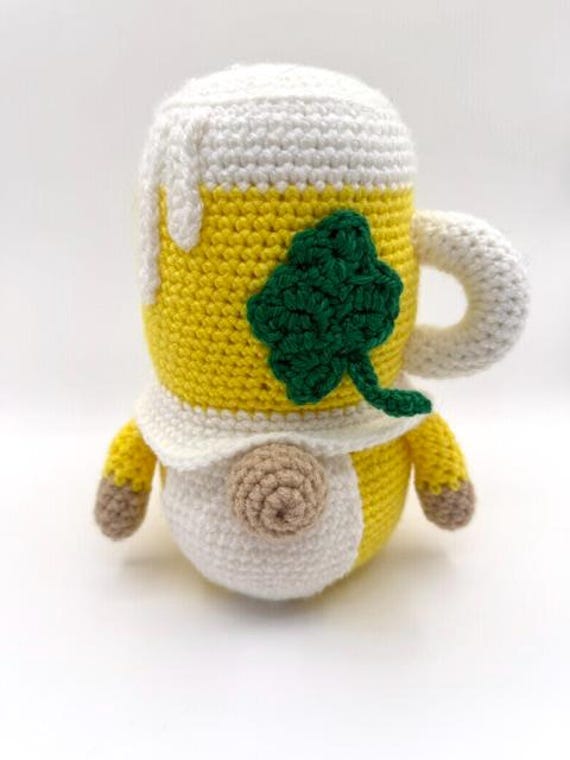 A handmade crochet gnome clutching a tiny beer mug — the kind of absurdly specific craft object that makes people laugh and then immediately want one.