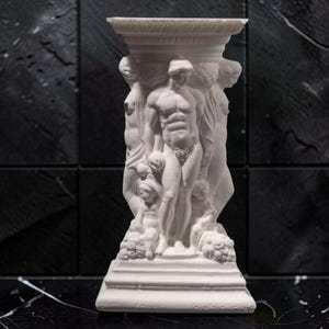 May include: A white, classical-style pedestal with sculpted figures. The pedestal features a square base, a central column adorned with multiple human figures, and a flat top. The figures are detailed and appear to be in a relief style.