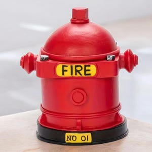 May include: A red fire hydrant figurine with the word "FIRE" in yellow lettering. The base has "NO 01" in yellow. The hydrant is a decorative item, likely a collectible or a novelty item.