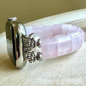 May include: A silver Apple Watch with a pink rose quartz band. The band is made of smooth, polished stones and has a silver clasp.