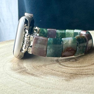 May include: A silver Apple Watch with a green, brown, and purple agate beaded band.