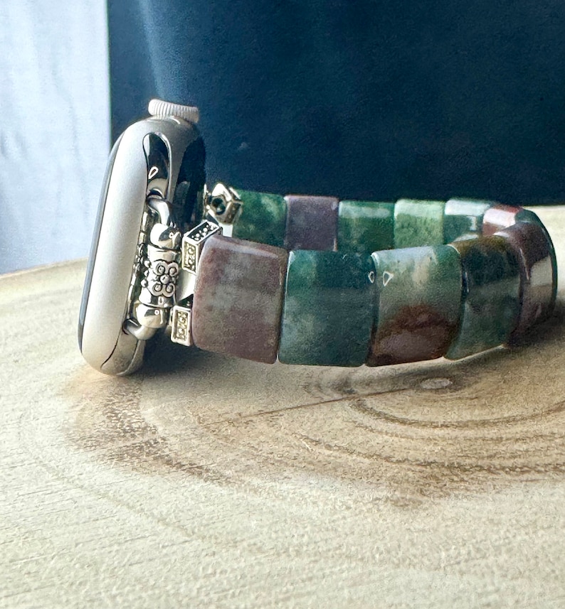 May include: A silver Apple Watch with a green, brown, and purple agate beaded band.