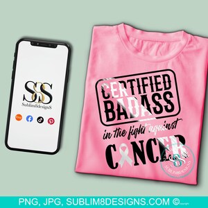 Könnte beinhalten: Ein pinkfarbenes T-Shirt mit dem Text "CERTIFIED BADASS in the fight against CANCER" in Schwarz und Weiß. Ein Smartphone zeigt ein Logo und Social-Media-Symbole an. Das Bild enthält auch eine Website-Adresse.