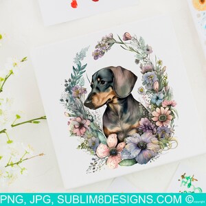 May include: A watercolour illustration of a dachshund dog surrounded by a wreath of flowers. The dog is black and brown with a pink nose and is looking to the left. The flowers are in shades of pink, purple, and blue.