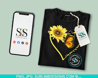 May include: A black t-shirt with a yellow sunflower and orange butterfly design. The text "A big piece of my heart" is written in a yellow heart shape. The design also includes the text "SS Sublim8Designs" in a circle.